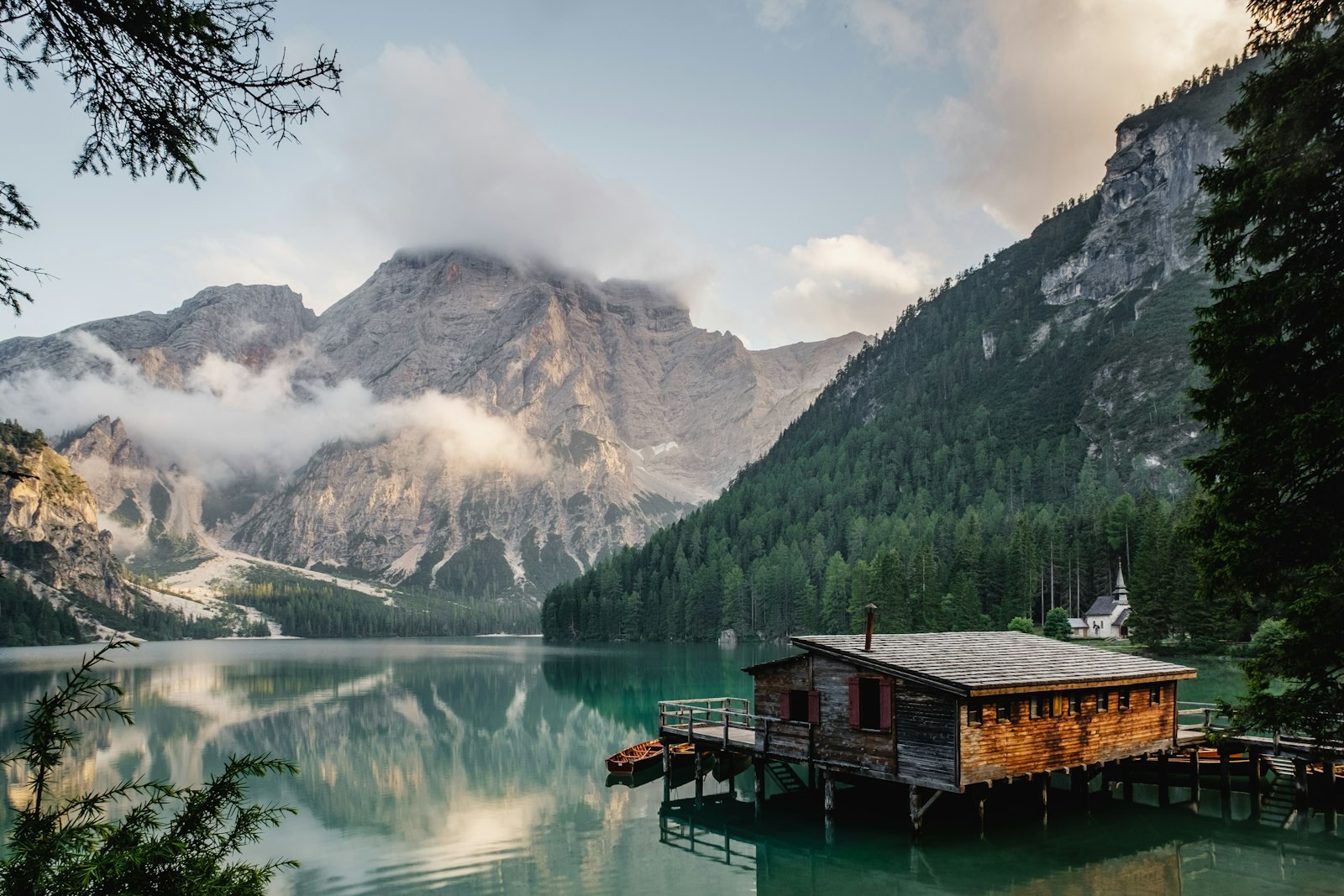 A timber boathouse on a still alpine lake at first light — the landscape that surrounds Optionventurebeam